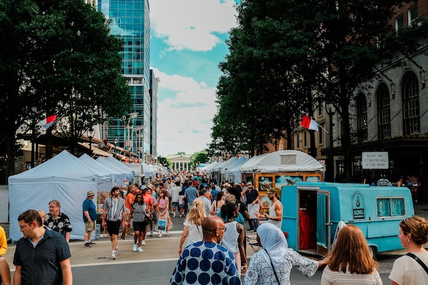 Visitors browsing juried art booths at Artsplosure