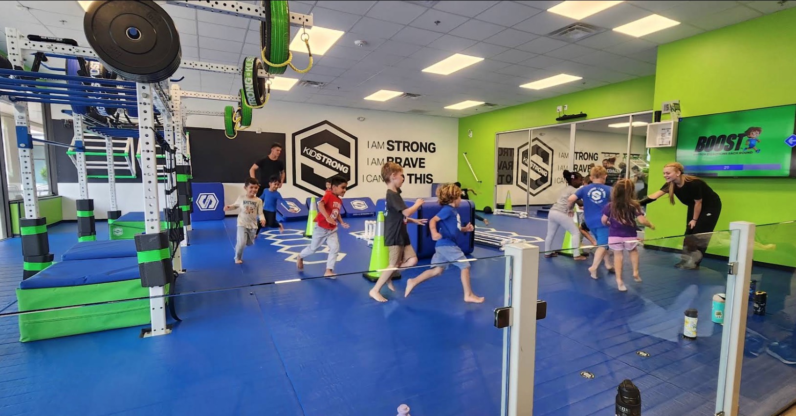 Young girl practicing balance on a gymnastics beam with an instructor's support at Little Gym of North Raleigh/Wake Forest